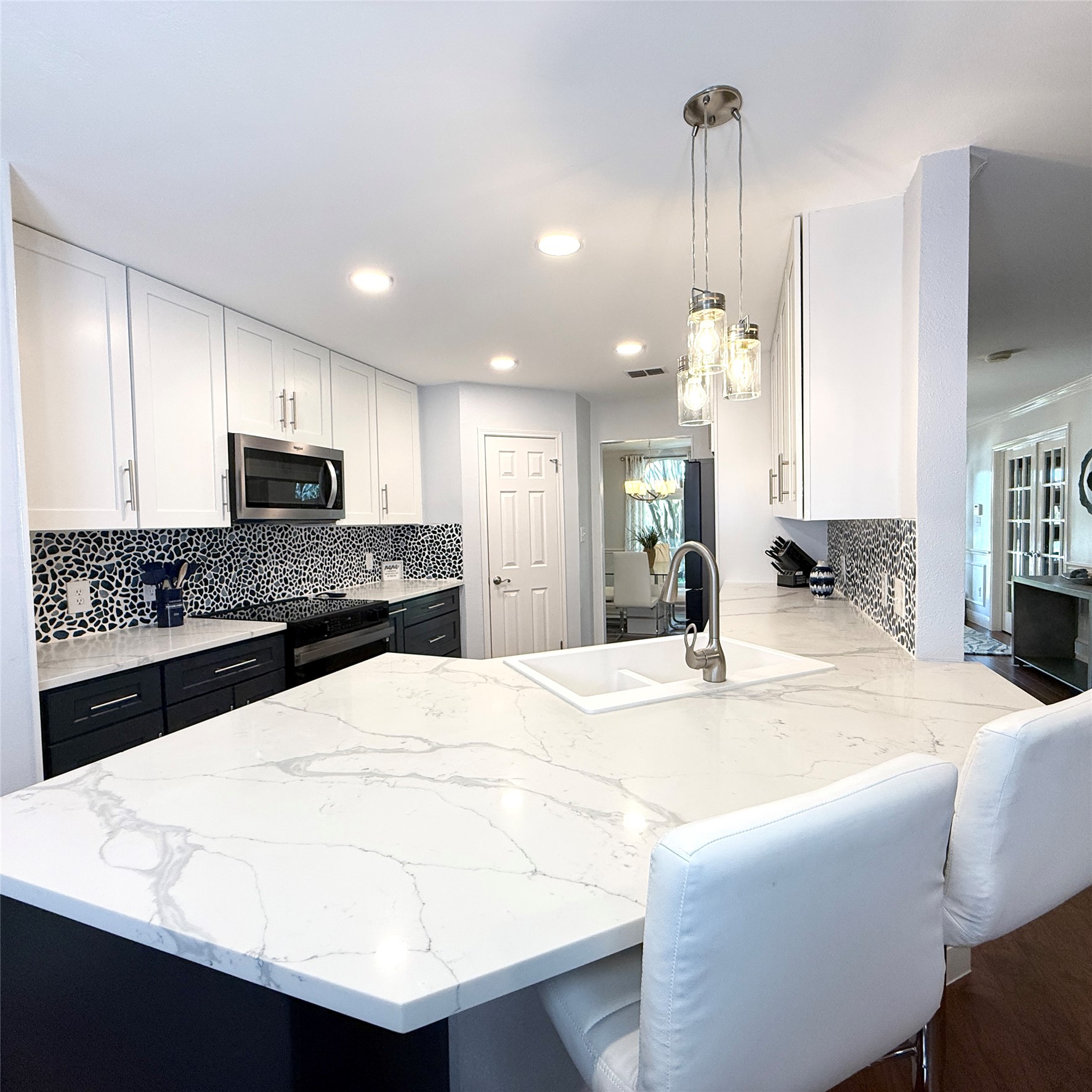 1902 Rowe Loop Pflugerville, TX 78660 - Photo 10 of 38 Kitchen featuring a peninsula, light quartz counters, decorative light fixtures, two tone color scheme, and stainless steel appliances