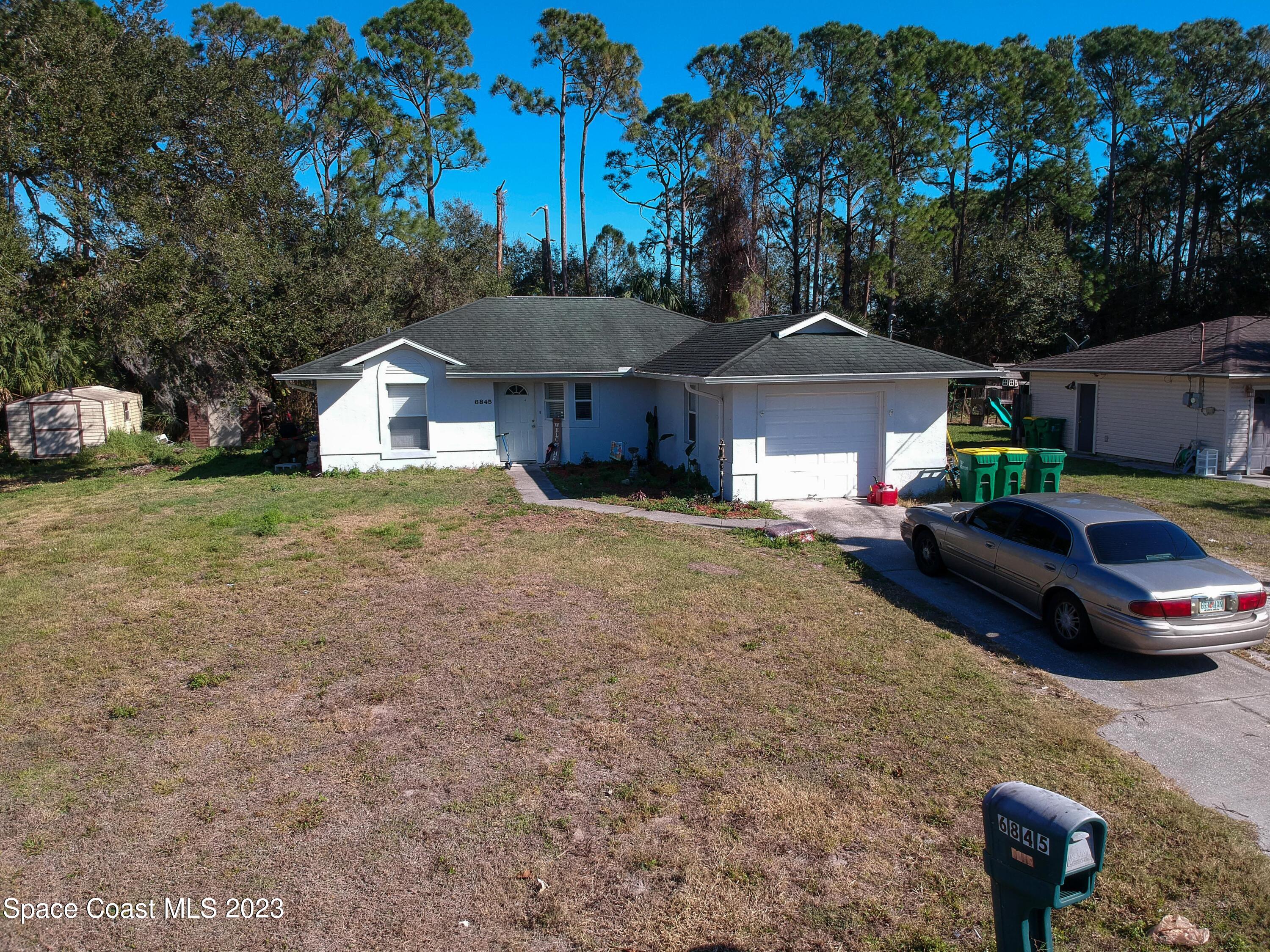 6845 Spring Street Cocoa, FL 32927 - Photo 2 of 45 a car parked in front of a house with a yard