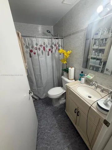 a bathroom with a sink a toilet and shower curtain
