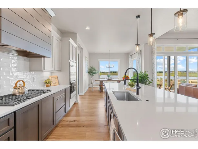 a large kitchen with kitchen island a stove a sink a center island and wooden floor