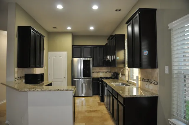 a kitchen with stainless steel appliances granite countertop a sink a stove and a refrigerator