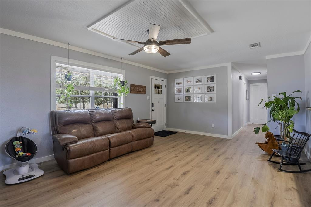 472 Cox Road Waxahachie, TX 75167 - Photo 3 of 31 Spacious room featuring wood-finish flooring, light gray walls, a large window, and a ceiling fan with beadboard detailing