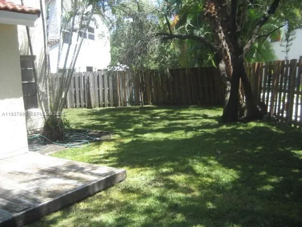 a backyard of a house with large trees and wooden fence