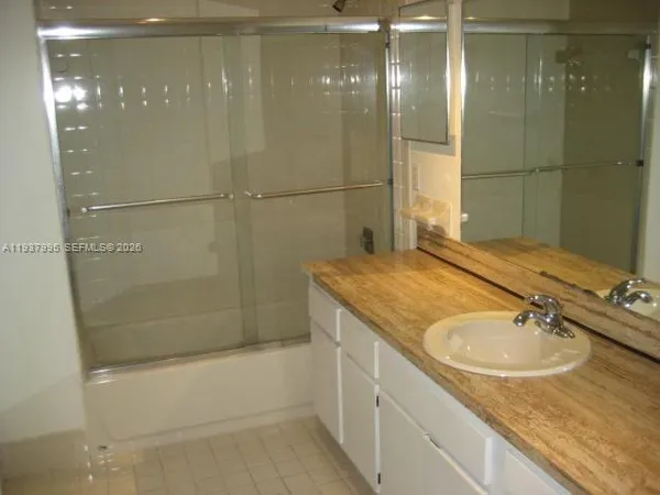 a bathroom with a granite countertop sink a mirror and shower