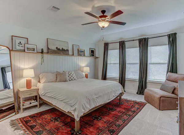 a bedroom with a bed a couch and a ceiling fan