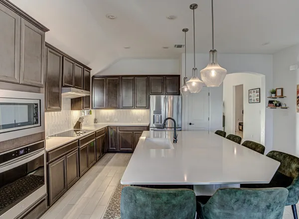 a large kitchen with stainless steel appliances a stove a sink dishwasher a refrigerator white cabinets and wooden floor