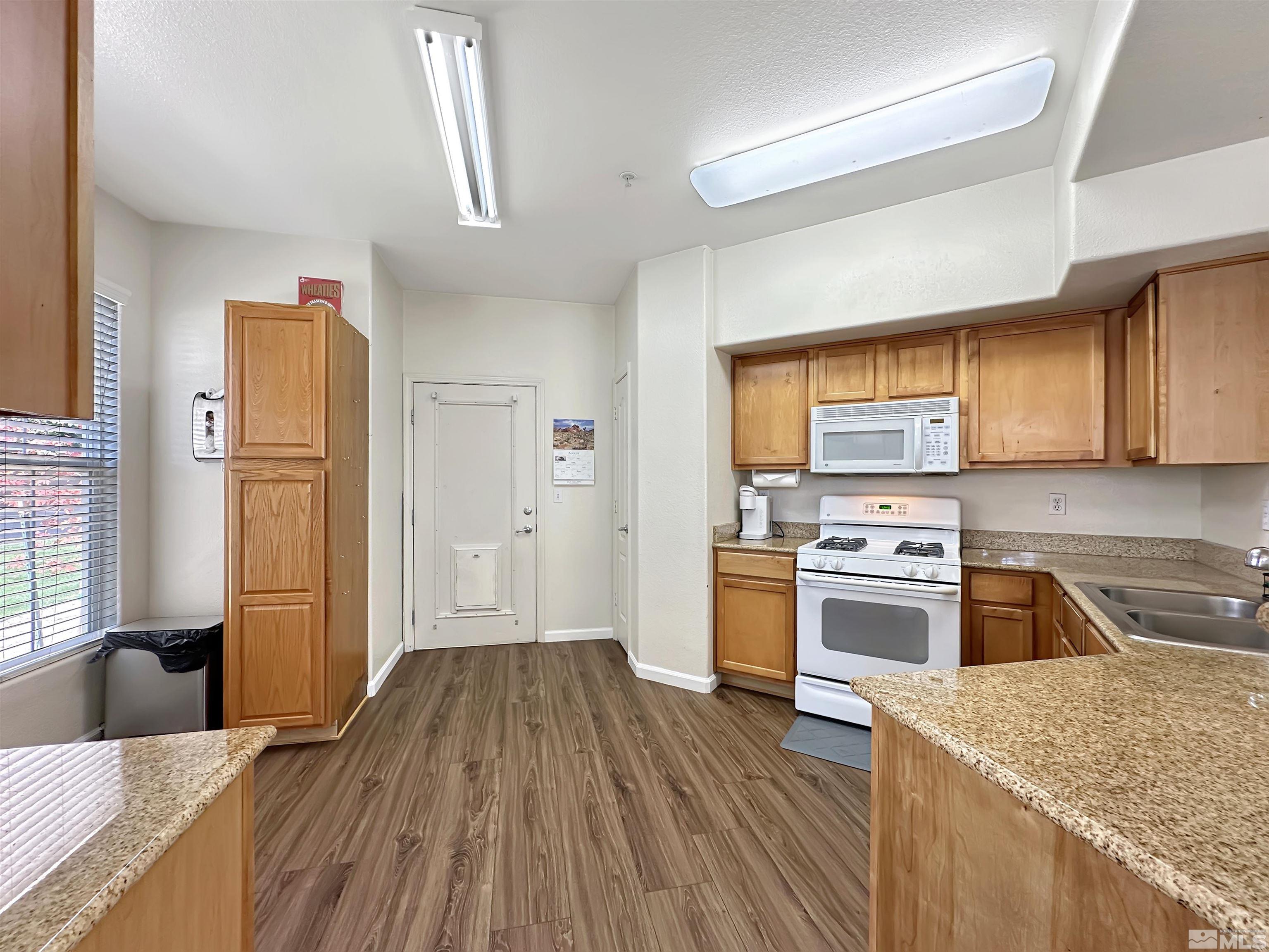 9050 Double R Boulevard, Unit 311 Reno, NV 89521 - Photo 11 of 37 a kitchen with stainless steel appliances granite countertop a refrigerator a sink dishwasher a stove and white countertops with wooden floor