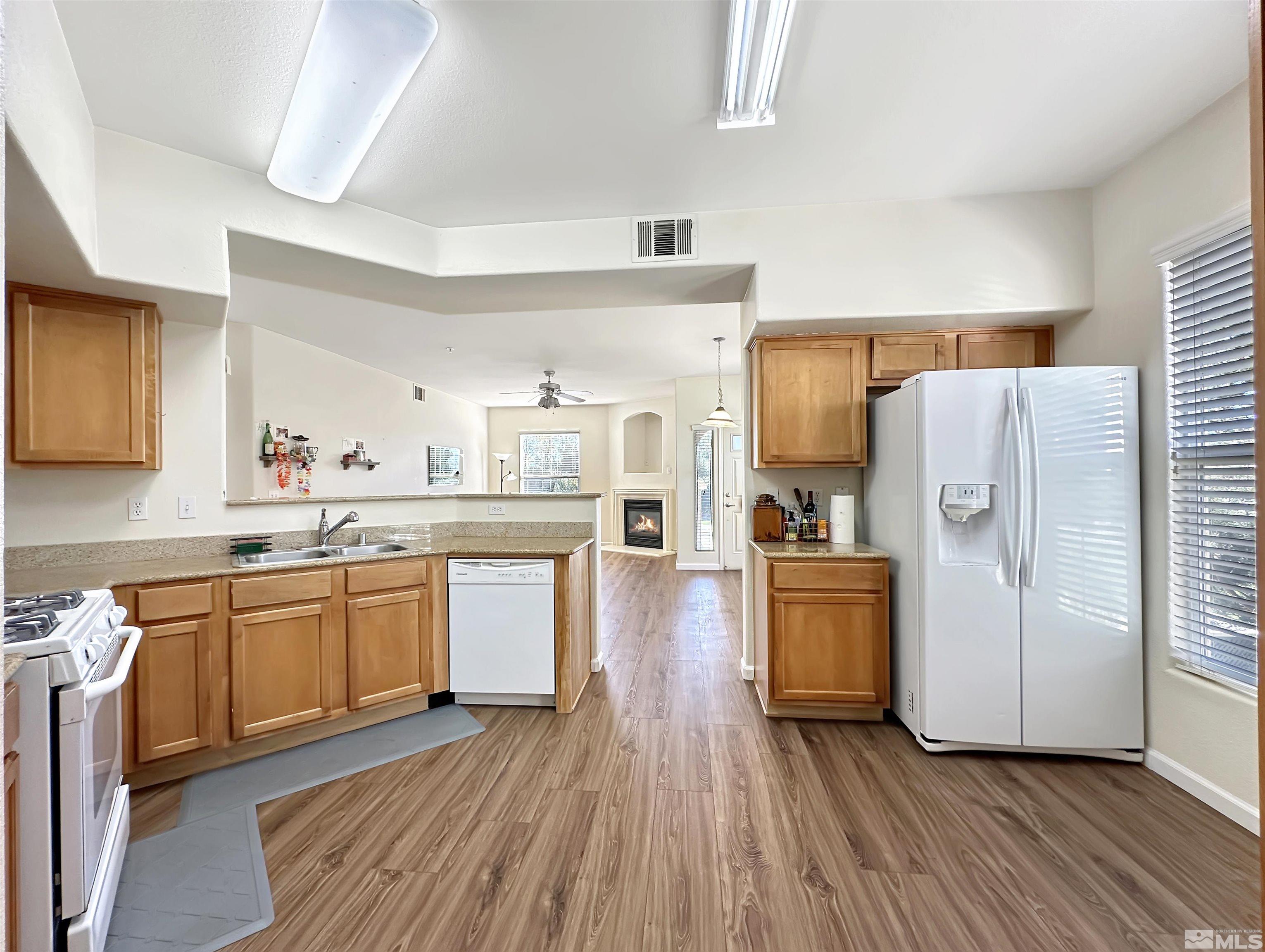 9050 Double R Boulevard, Unit 311 Reno, NV 89521 - Photo 12 of 37 a kitchen with granite countertop wooden floors and white stainless steel appliances