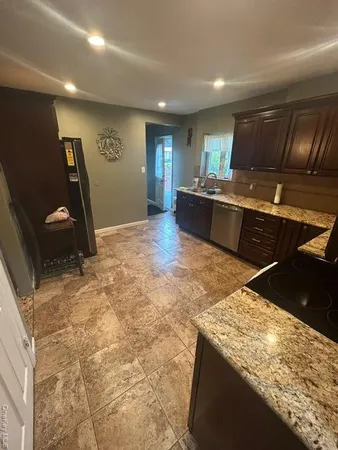 a living room with stainless steel appliances kitchen island granite countertop furniture and a refrigerator