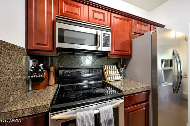 a kitchen with stainless steel appliances granite countertop a sink a stove and a refrigerator
