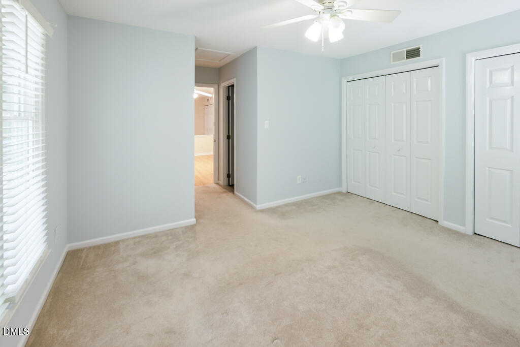 2831 Edridge Court, Unit 202 Raleigh, NC 27612 - Photo 23 of 33 an empty room with a chandelier fan and windows