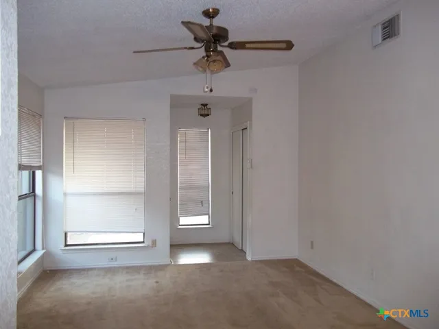 an empty room with windows and ceiling fan