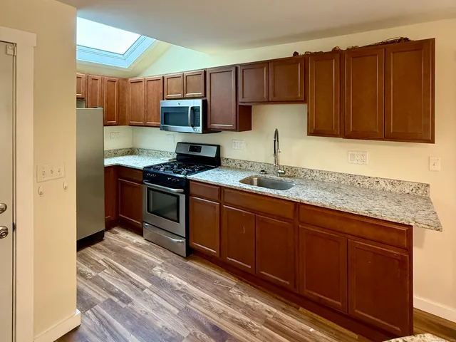 a kitchen with granite countertop wooden cabinets stainless steel appliances and a counter space