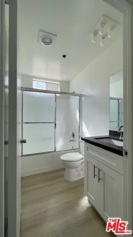 a bathroom with a granite countertop sink a toilet and shower