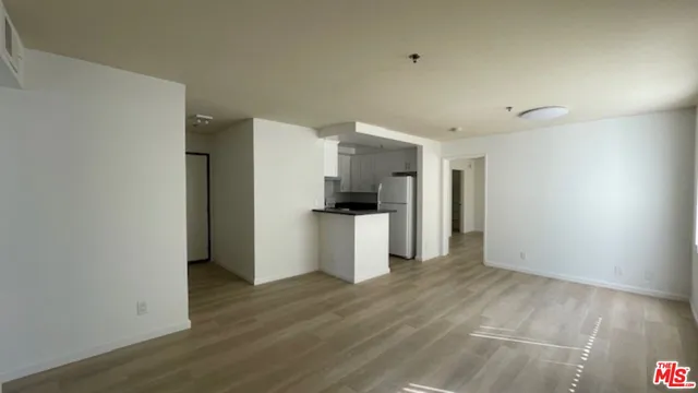 a view of a kitchen with a refrigerator a stove top oven and wooden floor