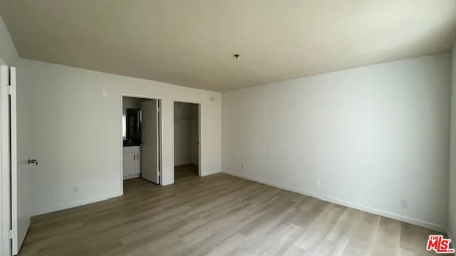 a view of an empty room with wooden floor and closet