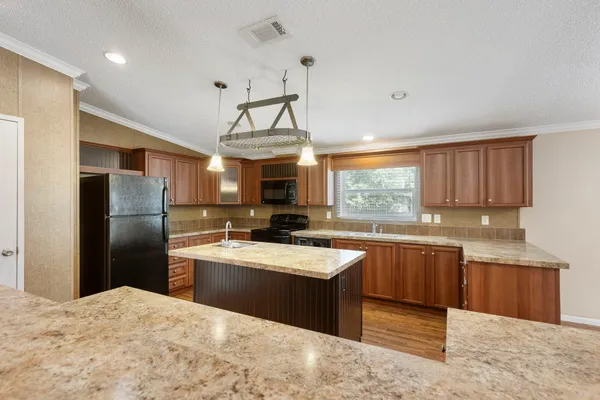 a kitchen with stainless steel appliances granite countertop a sink a stove a refrigerator cabinets and a window