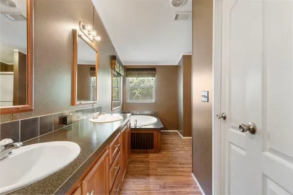 a spacious bathroom with a granite countertop double vanity sink a mirror and a shower