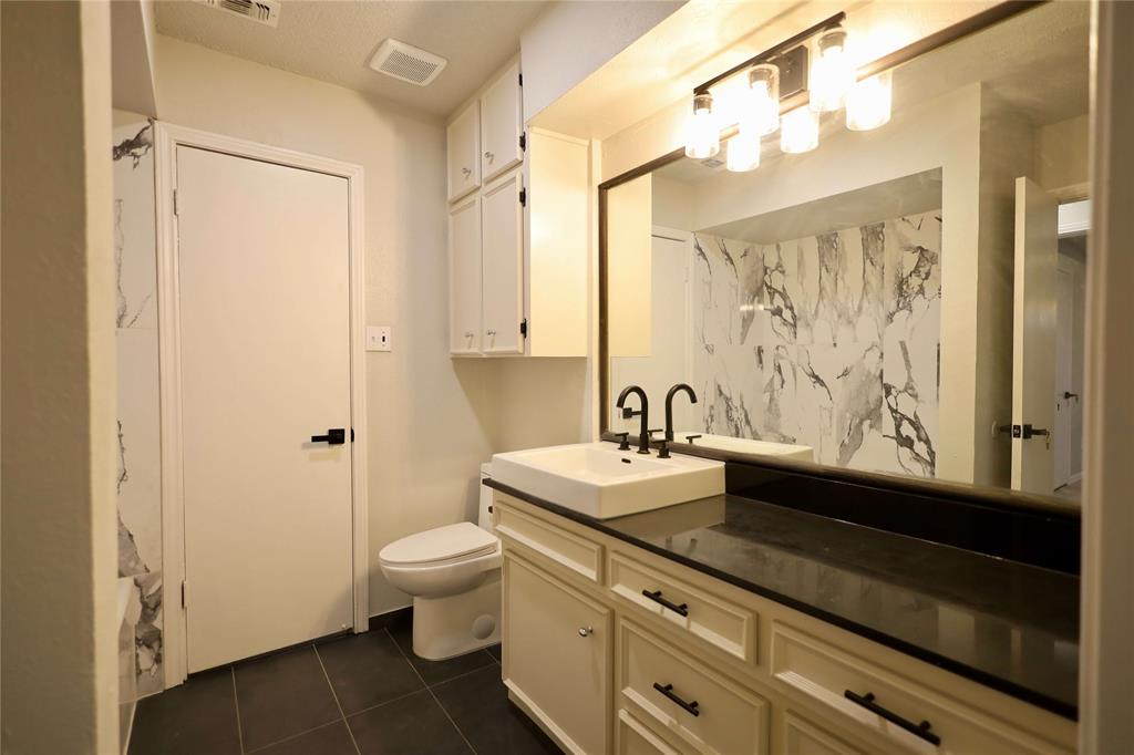 905 Pine Tree Lane DeSoto, TX 75115 - Photo 8 of 11 Full bath with vanity and dark tile patterned flooring