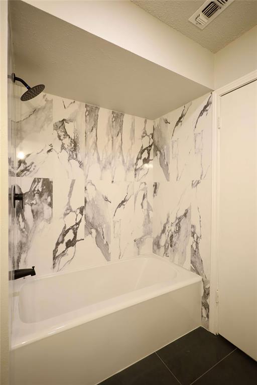 905 Pine Tree Lane DeSoto, TX 75115 - Photo 9 of 11 Full bathroom featuring dark tile patterned floors, a textured ceiling, and shower / bath combination