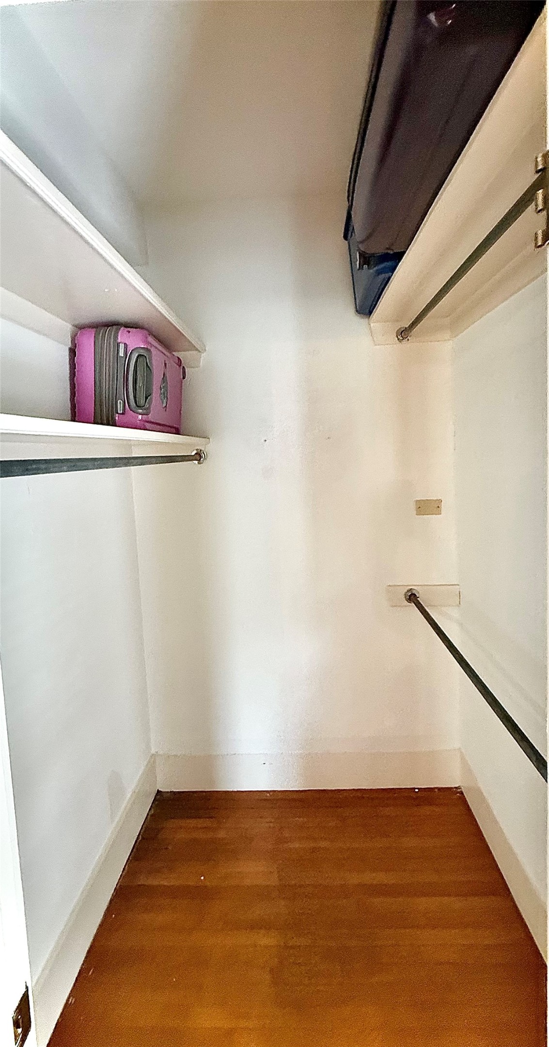 423 South Main Street Lockhart, TX 78644 - Photo 13 of 26 Closet storage featuring wood-finish flooring, white walls, multiple shelving units, and clothing rods for organization