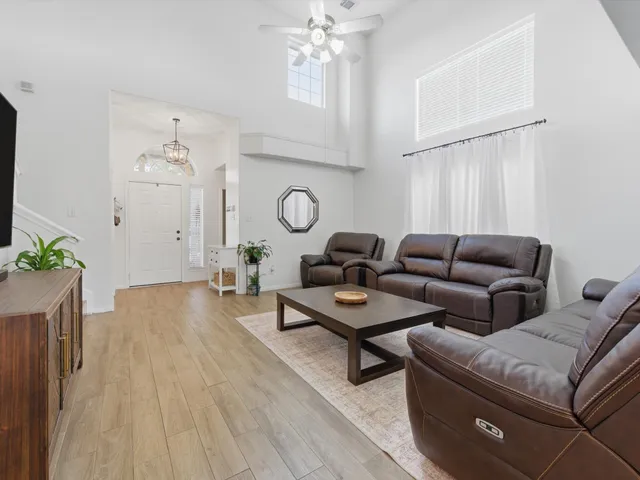 a living room with furniture a large window and wooden floor