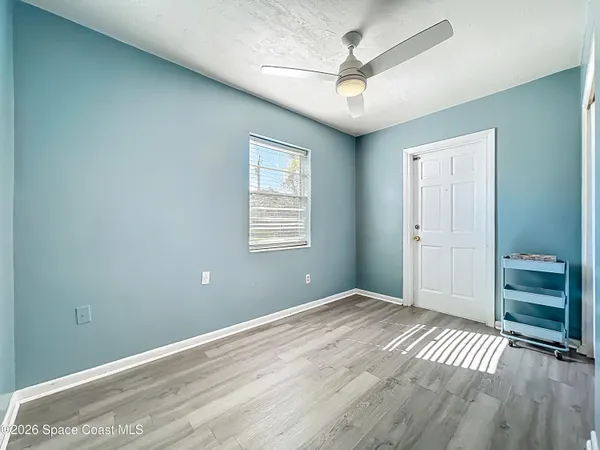 a view of empty room with wooden floor and fan