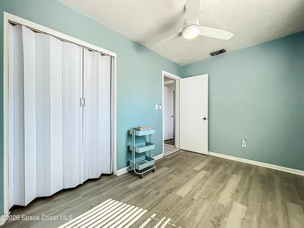 a view of a room with wooden floor and a ceiling fan