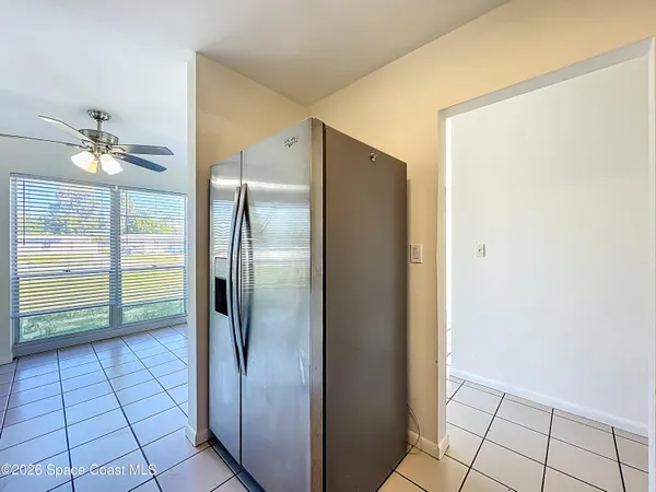 a view of a refrigerator in kitchen and an empty room in wooden floor