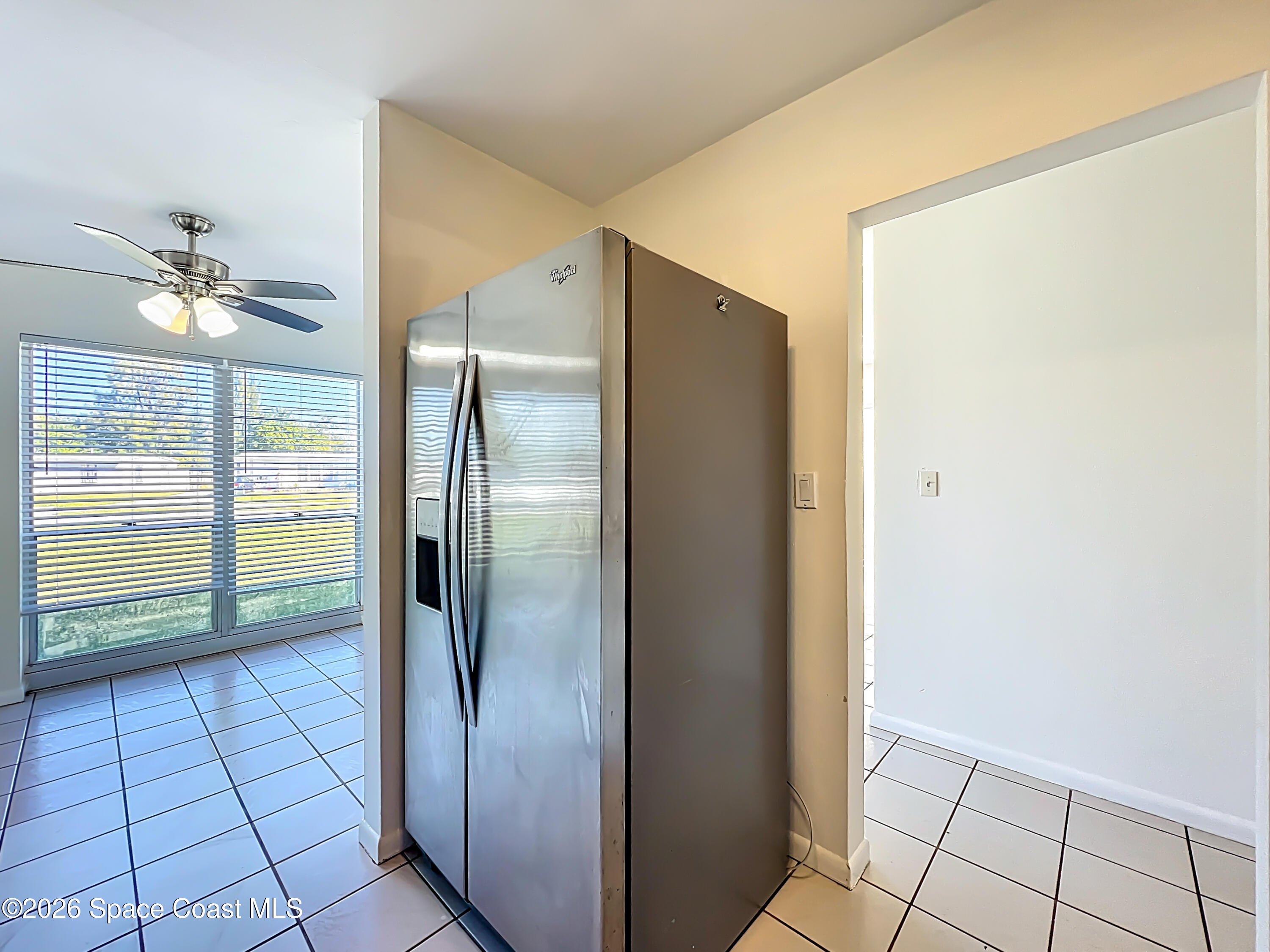 1090 Bianca Drive Northeast Palm Bay, FL 32905 - Photo 7 of 30 a view of a refrigerator in kitchen and an empty room in wooden floor