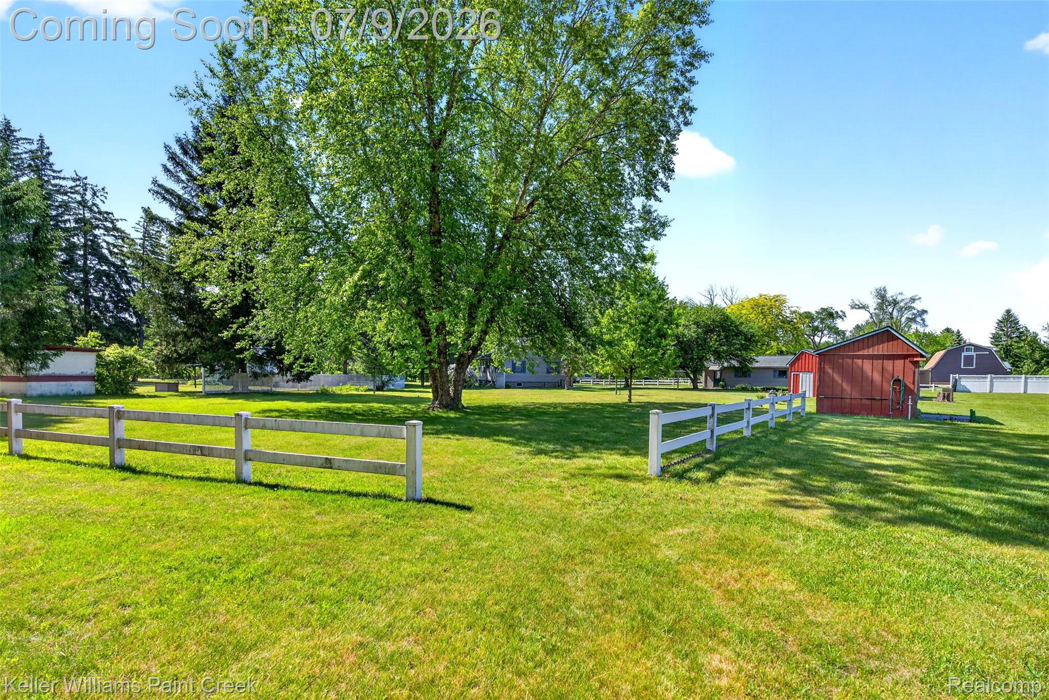 204 Russell Road Kawkawlin, MI 48631 - Photo 18 of 82 Expansive green lawn with mature trees and a white split-rail fence
