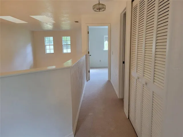 a view of a hallway with wooden floor and windows