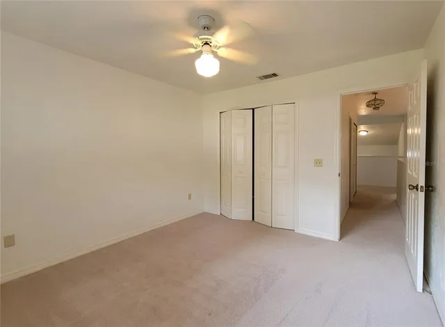 an empty room with a ceiling fan and a bathroom