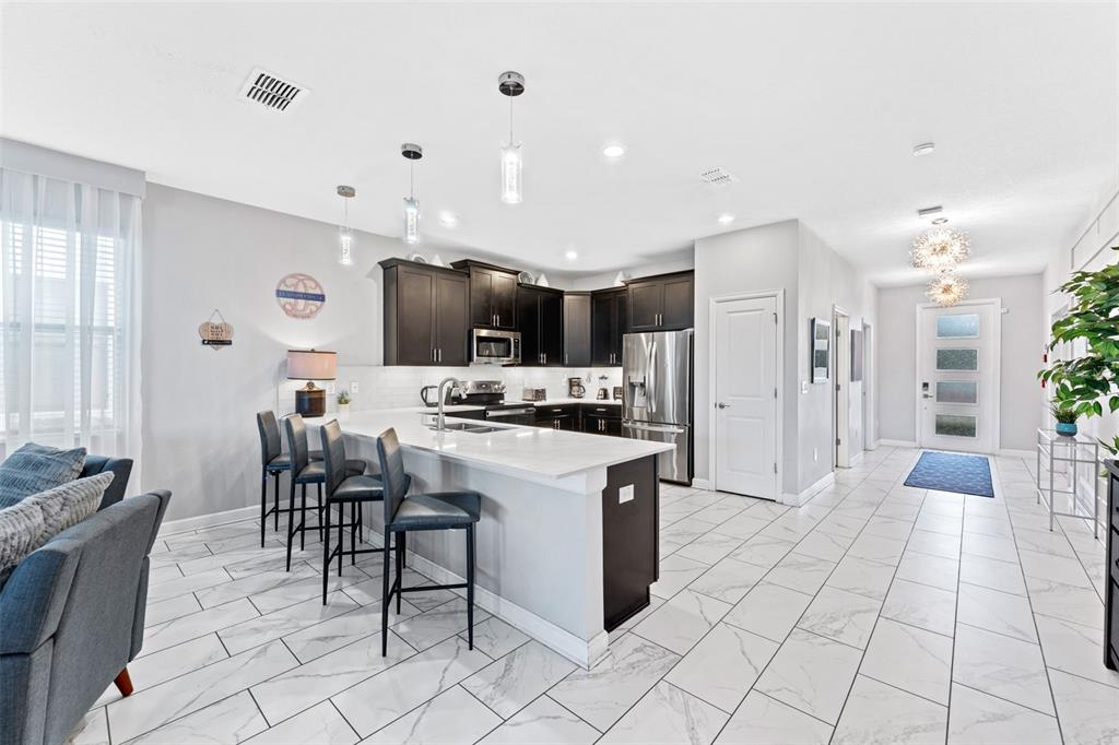 2933 Fable Street Kissimmee, FL 34746 - Photo 5 of 53 a kitchen with stainless steel appliances kitchen island granite countertop a refrigerator and a stove top oven