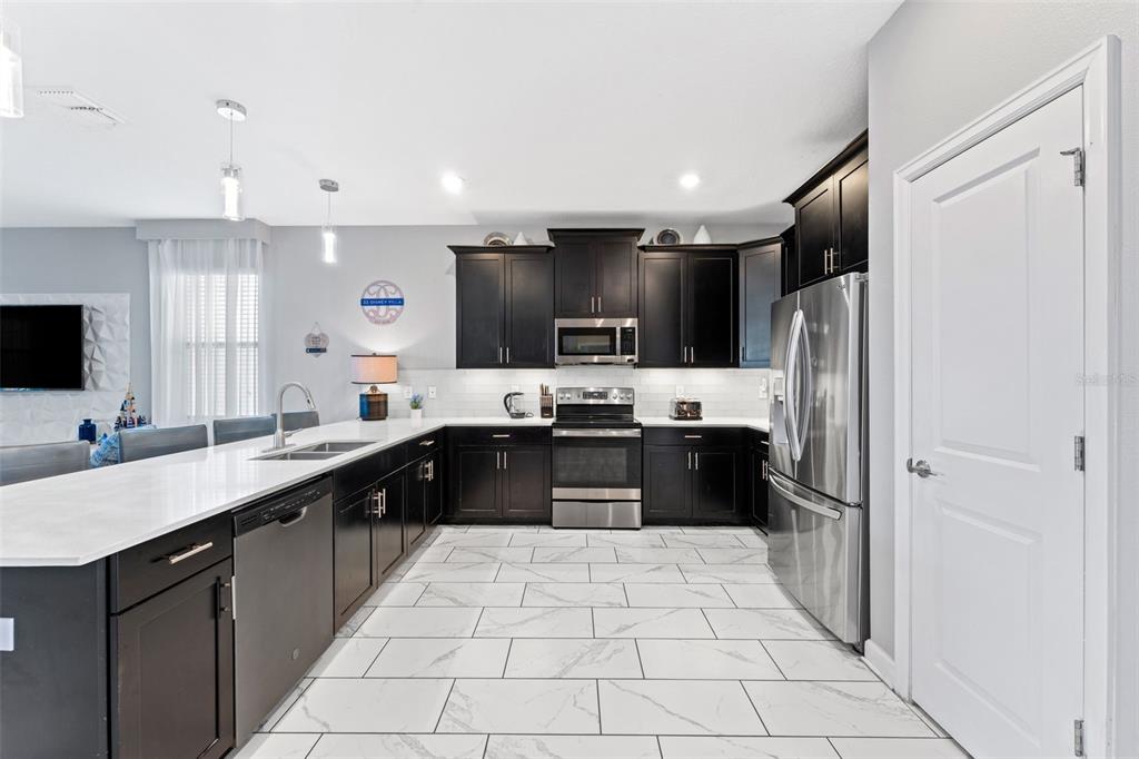 2933 Fable Street Kissimmee, FL 34746 - Photo 7 of 53 a large kitchen with a large counter top stainless steel appliances and cabinets