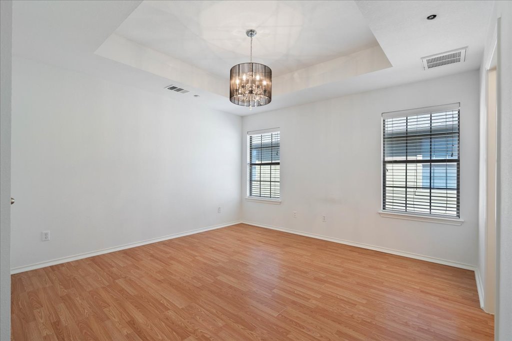 14815 Avery Ranch Boulevard, Unit 302 Austin, TX 78717 - Photo 15 of 28 an empty room with wooden floor chandelier fan and windows