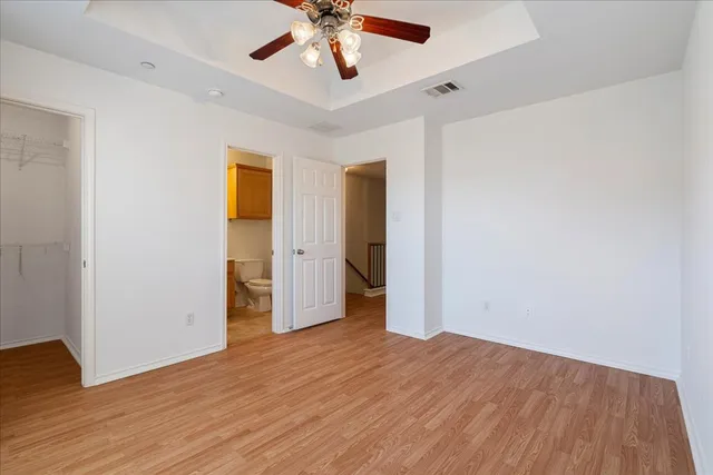 an empty room with wooden floor and ceiling fan