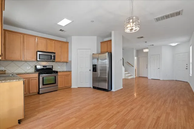 a kitchen with stainless steel appliances granite countertop a refrigerator oven a sink dishwasher and a stove with wooden floor