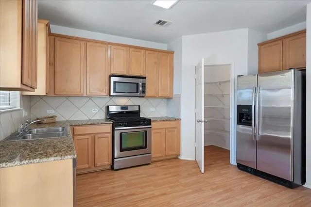 a kitchen with granite countertop wooden cabinets stainless steel appliances and a counter space
