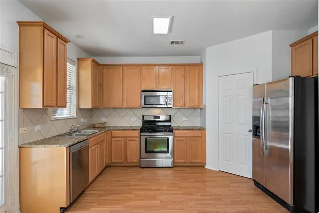a kitchen with stainless steel appliances granite countertop a stove a refrigerator and a sink