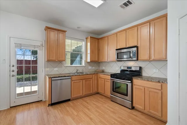 a kitchen with stainless steel appliances granite countertop a stove a sink and a microwave