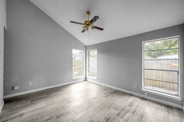 an empty room with wooden floor fan and windows