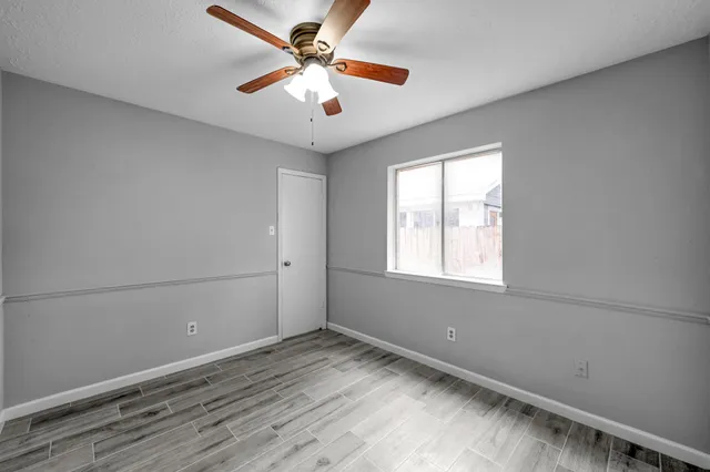 an empty room with a window and a ceiling fan