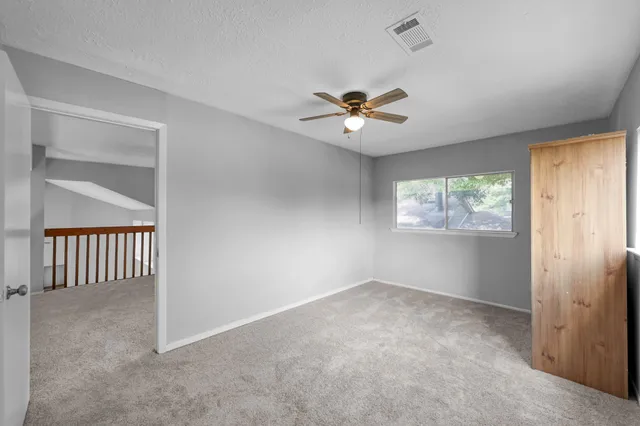 an empty room with windows and ceiling fan