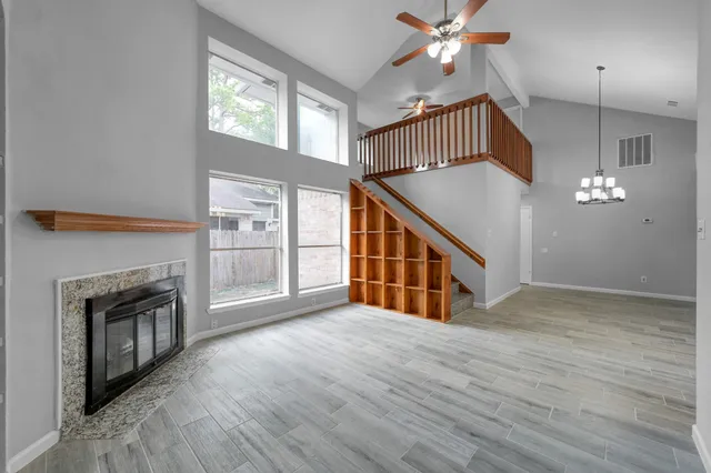 a view of an empty room with chandelier fan and a fireplace