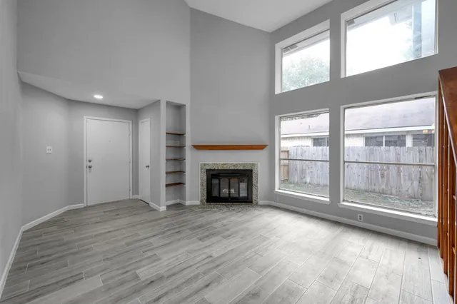a view of an empty room with a window and fireplace
