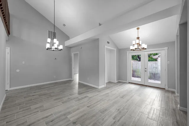 a view of an empty room with wooden floor and chandelier