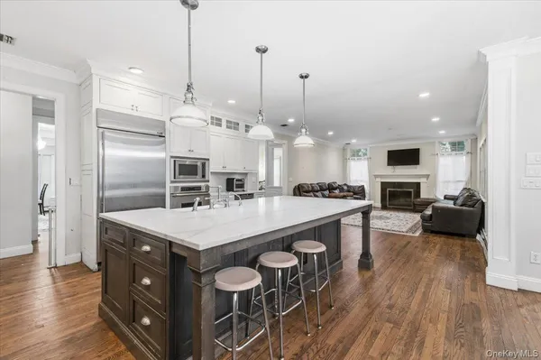 a large kitchen with kitchen island a stove a sink a refrigerator and a fireplace with wooden floor