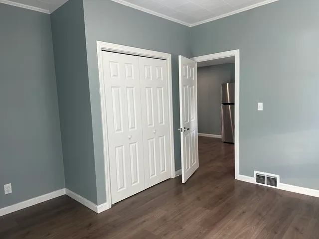 an empty room with wooden floor & closet and windows