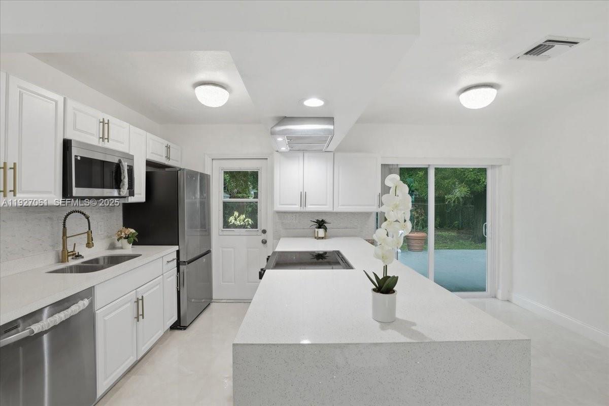a kitchen with granite countertop a sink stainless steel appliances and cabinets